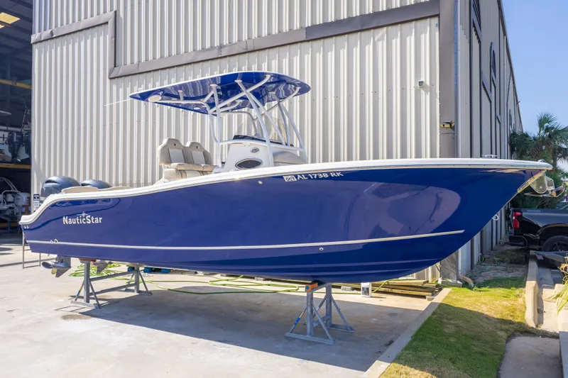 The Image of 2017 NauticStar 2602 Legacy boat in blue, displayed outdoors on stands. - 0