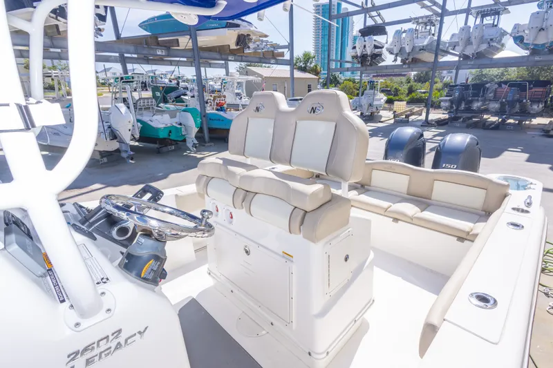 Slide: The Image of 2017 NauticStar 2602 Legacy boat interior with helm, seating, and docked boats in background. - 34