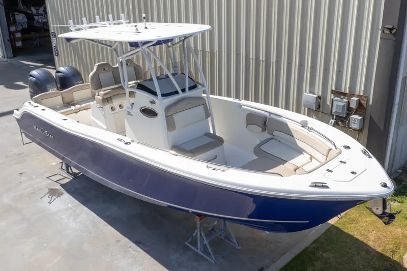 Slide: The Image of 2017 NauticStar 2602 Legacy boat with dual engines, docked near a metal building. - 4