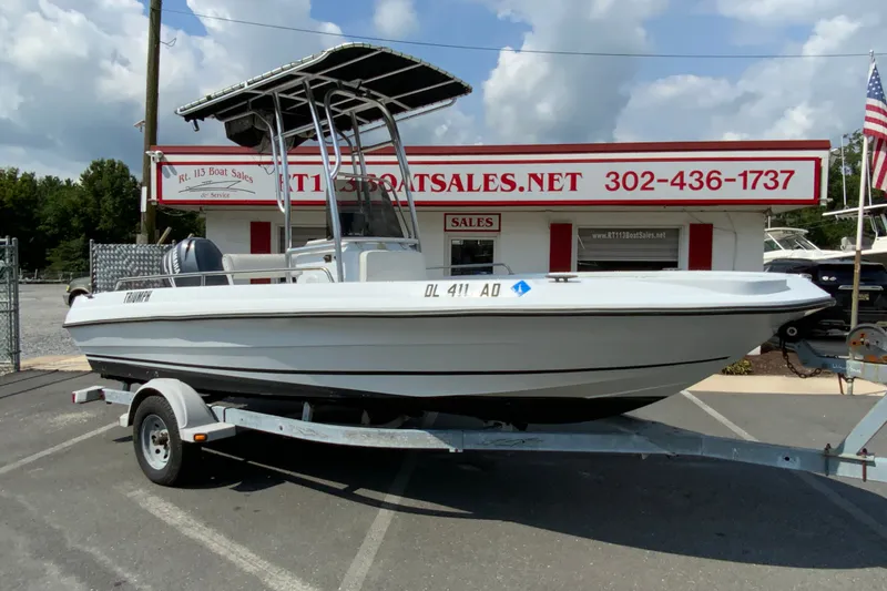 Slide: The Image of 2004 Triumph 190 Bay boat on trailer at dealership, clear sky background. - 2
