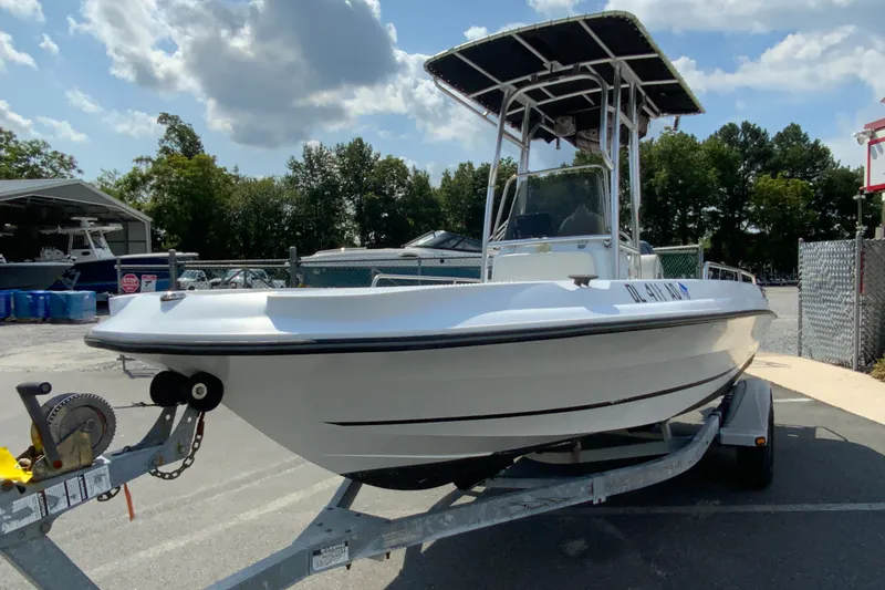 Slide: The Image of 2004 Triumph 190 Bay boat on trailer, parked outdoors under a partly cloudy sky. - 4