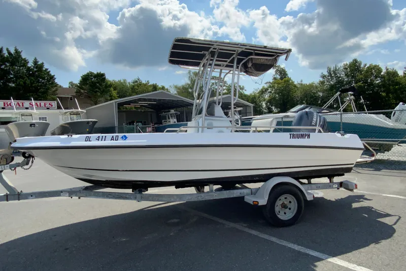Slide: The Image of 2004 Triumph 190 Bay boat on trailer at dealership under cloudy sky. - 5
