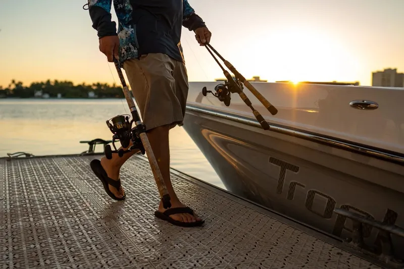 Slide: The Image of Man carrying fishing rods near 2026 Bayliner Trophy T24CC boat at sunset. - 8