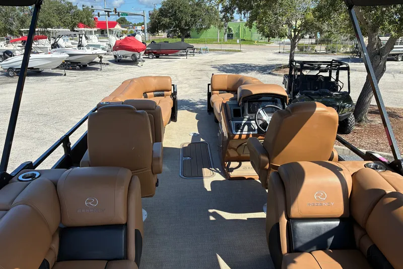 Slide: The Image of 2024 Regency 230 LE3 pontoon boat with luxurious tan seating and modern dashboard. - 5