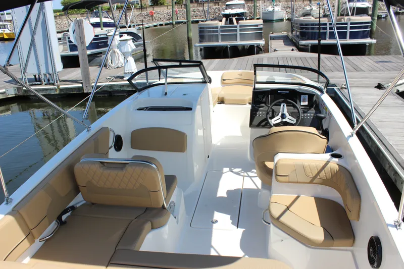 Slide: The Image of 2026 Bayliner VR6 Bowrider OB interior with tan seating at marina dock. - 7