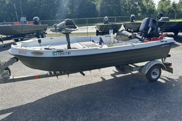 Slide: The Image of 2003 Pelican Predator boat on trailer, parked outdoors, with motor and fishing equipment. - 2