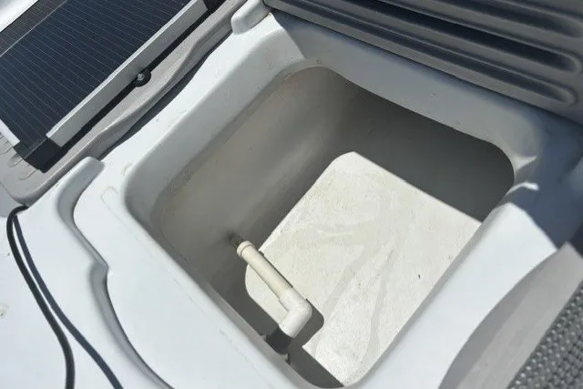 Slide: The Image of Interior compartment of a 2003 Pelican Predator boat, featuring a storage area with a drain. - 16