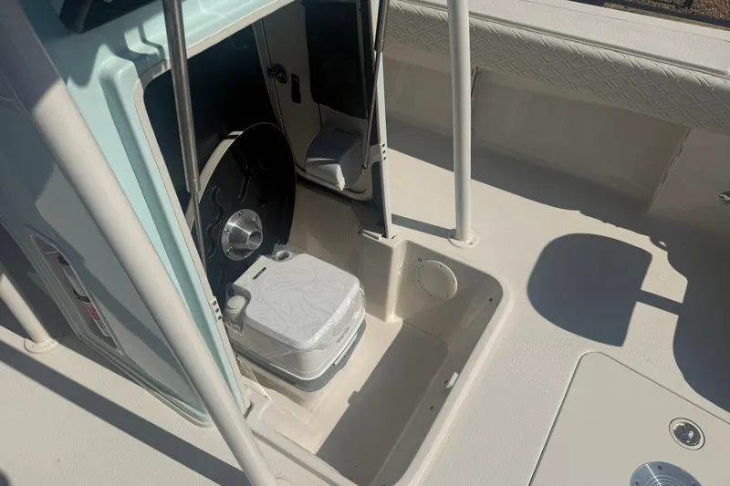 Slide: The Image of 2027 Carolina Skiff 26 Ultra Elite boat interior with storage compartment and portable toilet. - 22
