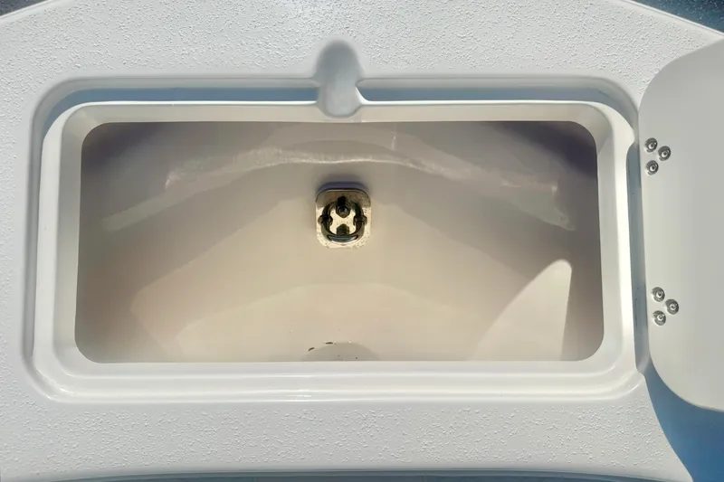 Slide: The Image of 2027 Carolina Skiff 26 Ultra Elite boat compartment with open lid and drain plug. - 15