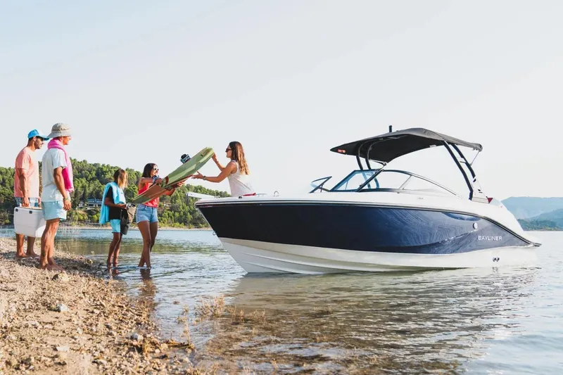 Slide: The Image of Manufacturer Provided Image: 2025 Bayliner V20 boat by shore with people loading supplies. - 1