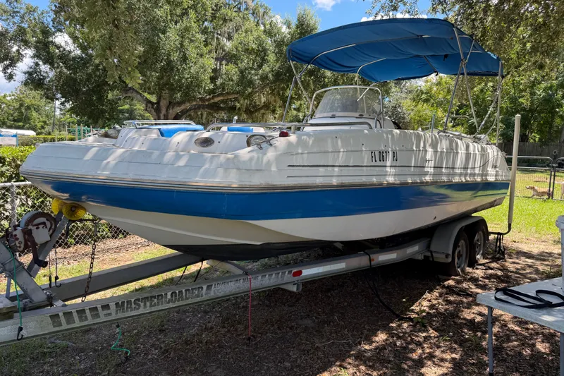 The Image of 2012 Hurricane Center Console 231 OB boat on trailer, parked outdoors under trees. - 0