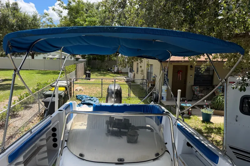 Slide: The Image of 2012 Hurricane Center Console 231 OB boat with blue canopy in a backyard setting. - 13