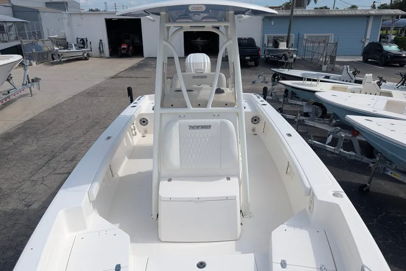 Slide: The Image of A modern boat with a center console and spacious deck, parked in a boatyard area. - 32
