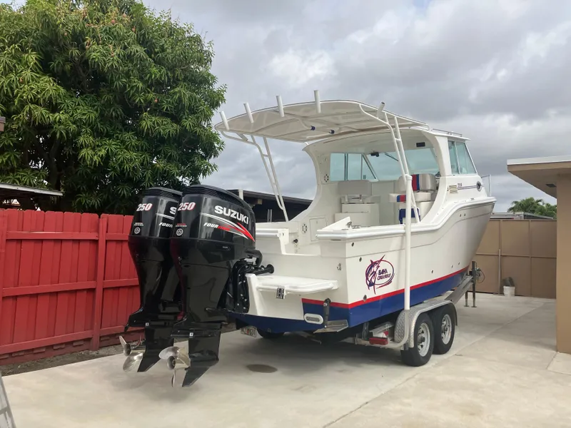Slide: The Image of 2000 Baha Cruisers 272 Sportfish boat with twin Suzuki 250 outboard motors on trailer. - 0