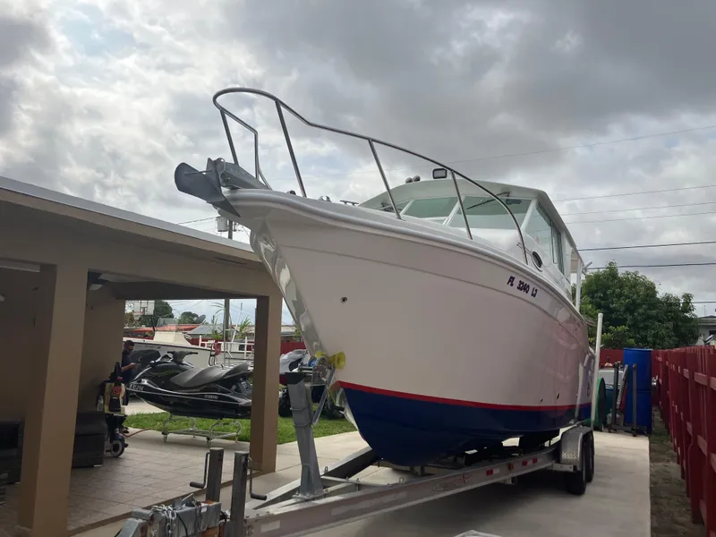 Slide: The Image of 2000 Baha Cruisers 272 Sportfish boat on a trailer in a driveway. - 3