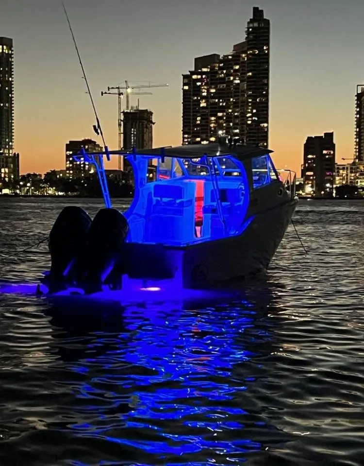 Slide: The Image of 2000 Baha Cruisers 272 Sportfish boat illuminated with blue lights at dusk. - 42