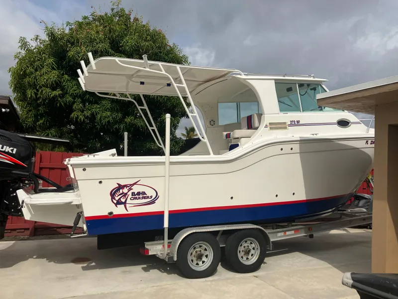 Slide: The Image of 2000 Baha Cruisers 272 Sportfish boat on a trailer in a driveway. - 1
