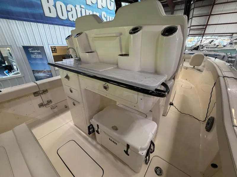 Slide: The Image of The image shows the cockpit of a 2027 Scout 260 LXF boat with a cooler and storage. - 42