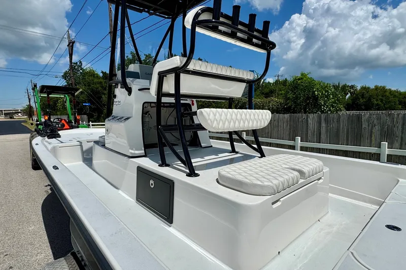Slide: The Image of 2025 Shallow Sport 24 Modified V boat with seating, parked outdoors under a blue sky. - 8