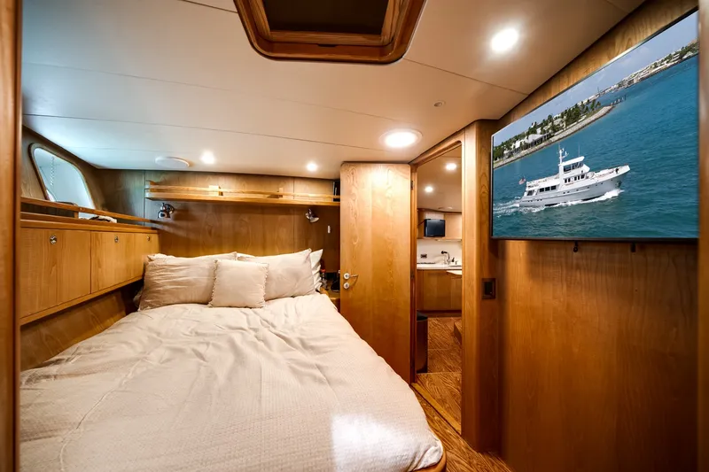 Slide: The Image of Cozy cabin with a double bed, wood paneling, and a large TV displaying a boat. - 47