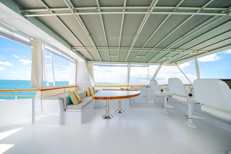 Slide: The Image of The image shows the deck of a 1992 Palmer Johnson 80 VRIPACK DOGGERS BANK. It features white seating and a wooden table. - 23