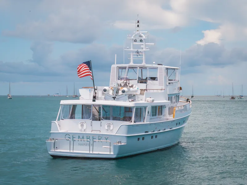 Slide: The Image of A white yacht with an American flag sails on calm waters under a cloudy sky. - 15