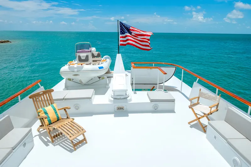 Slide: The Image of The deck of a luxury yacht with lounge chairs and an American flag, surrounded by blue water. - 28