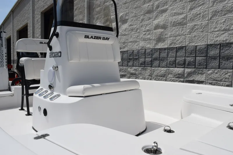 Slide: The Image of 2023 Blazer Bay 2020 boat interior with seating and controls, against a brick wall backdrop. - 8