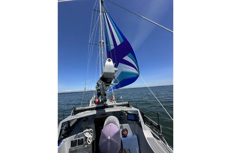 Slide: The Image of Sailing on a 2005 Brewer Cutter with vibrant blue and white sails on open water. - 65