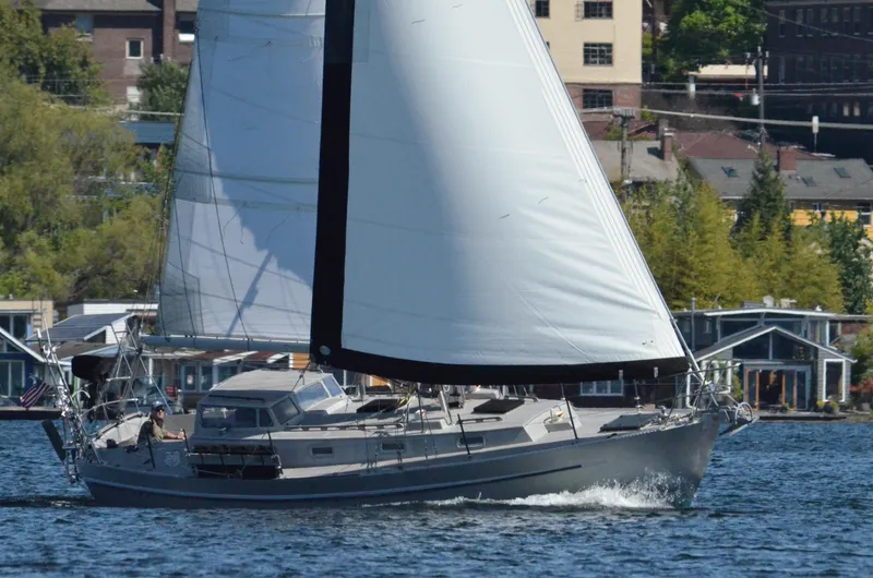 Slide: The Image of Eine graue Segelyacht segelt auf einem ruhigen Gewässer vor einer städtischen Kulisse. - 23