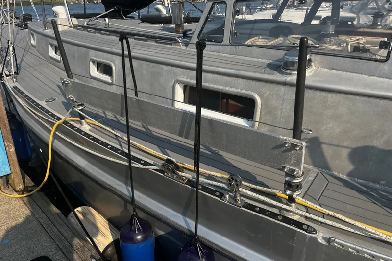 Slide: The Image of Side view of a 2005 Brewer Cutter sailboat docked, featuring deck details and mooring lines. - 34