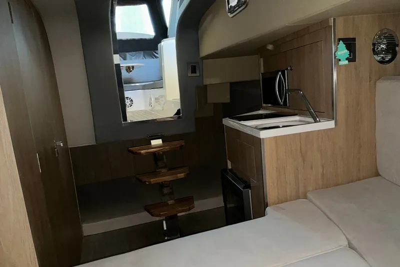 Slide: The Image of Interior of 2026 NX Boats 360 Sport Coupe with modern kitchenette and seating area. - 32