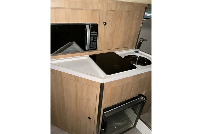 Slide: The Image of Compact kitchen area in 2026 NX Boats 360 Sport Coupe with microwave and sink. - 31
