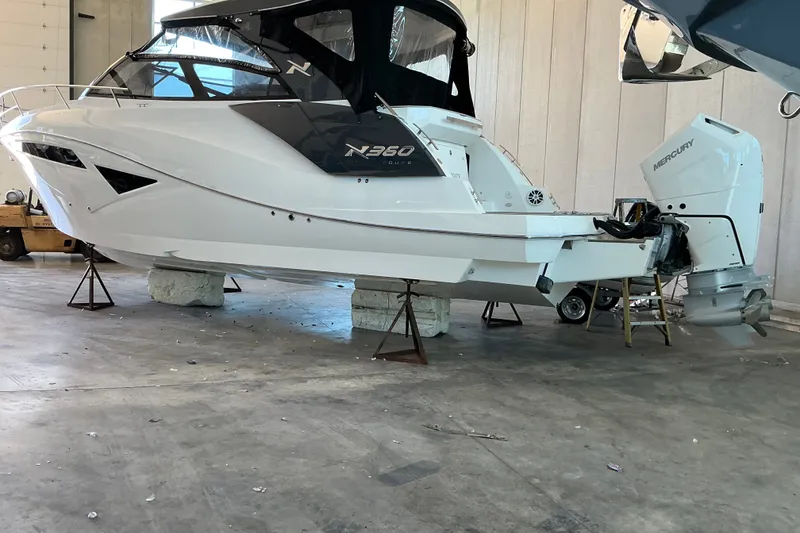 Slide: The Image of 2026 NX Boats 360 Sport Coupe in a garage, elevated on supports. - 11