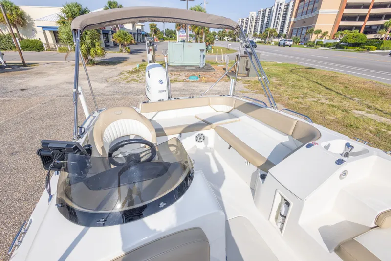 Slide: The Image of 2018 Stingray 192 SC boat interior with seating and steering wheel, parked near a road. - 29