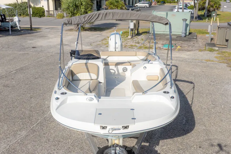 Slide: The Image of 2018 Stingray 192 SC boat with canopy, parked on pavement, showcasing interior seating. - 5