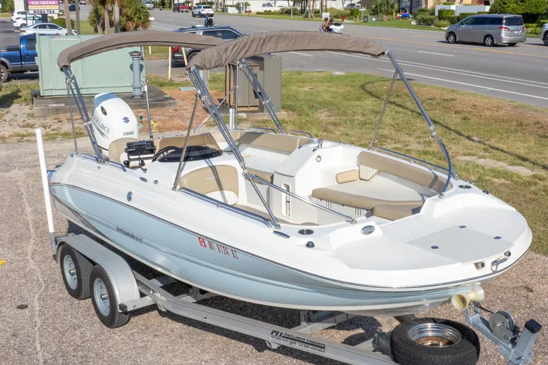 Slide: The Image of 2018 Stingray 192 SC boat on trailer, featuring a Suzuki 150 engine and bimini top. - 2