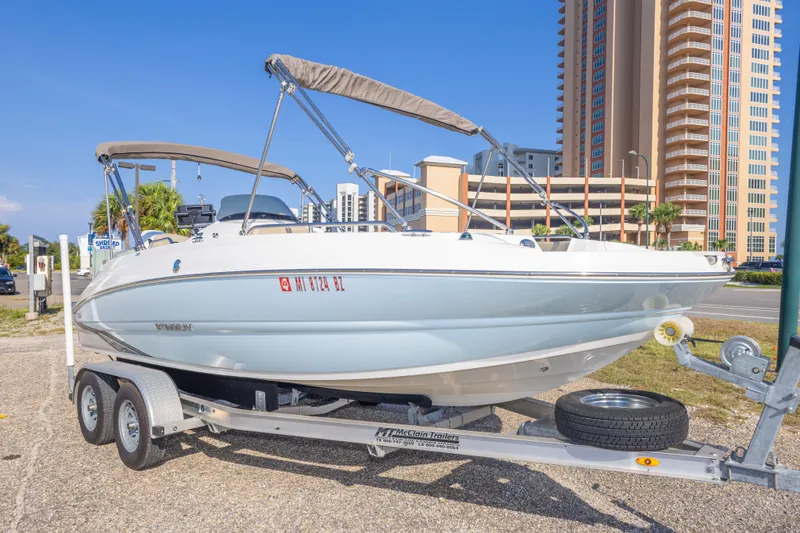 Slide: The Image of 2018 Stingray 192 SC boat on trailer, parked near tall buildings. - 11