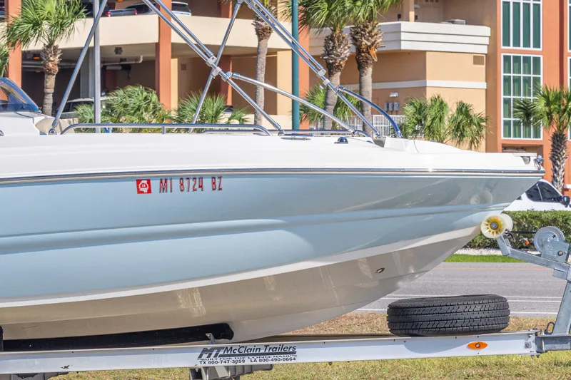 Slide: The Image of 2018 Stingray 192 SC boat on trailer, parked near palm trees and buildings. - 10