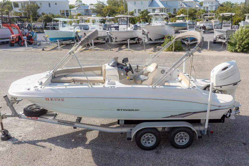 Slide: The Image of 2018 Stingray 192 SC boat on trailer, parked in marina with other boats. - 3