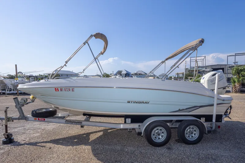 Slide: The Image of 2018 Stingray 192 SC boat on trailer with canopy, parked outdoors. - 17