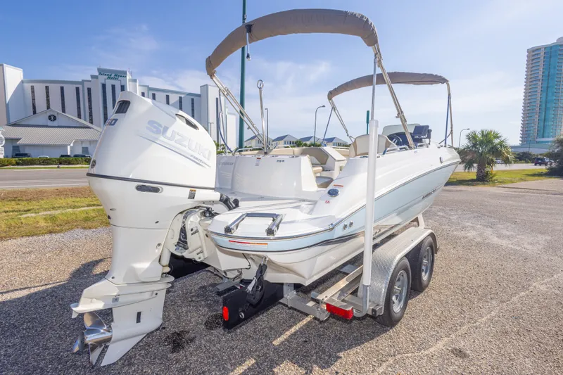 Slide: The Image of 2018 Stingray 192 SC boat on trailer with Suzuki outboard motor, parked near buildings. - 13