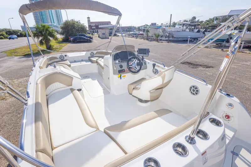 Slide: The Image of 2018 Stingray 192 SC boat interior with seating, steering console, and canopy in a marina setting. - 21