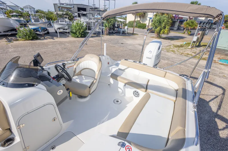 Slide: The Image of 2018 Stingray 192 SC boat interior with seating and steering wheel, parked outdoors. - 30
