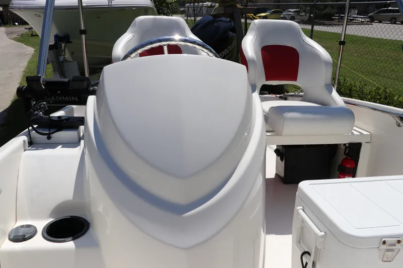 Slide: The Image of 2017 Boston Whaler 130 Super Sport interior with white and red seating, steering console, and equipment. - 19