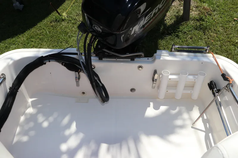 Slide: The Image of 2017 Boston Whaler 130 Super Sport boat interior with motor and rod holders. - 8