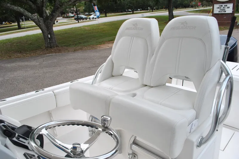 Slide: The Image of 2016 Regulator 28 Forward Seating boat with white leather seats and steering wheel. - 38
