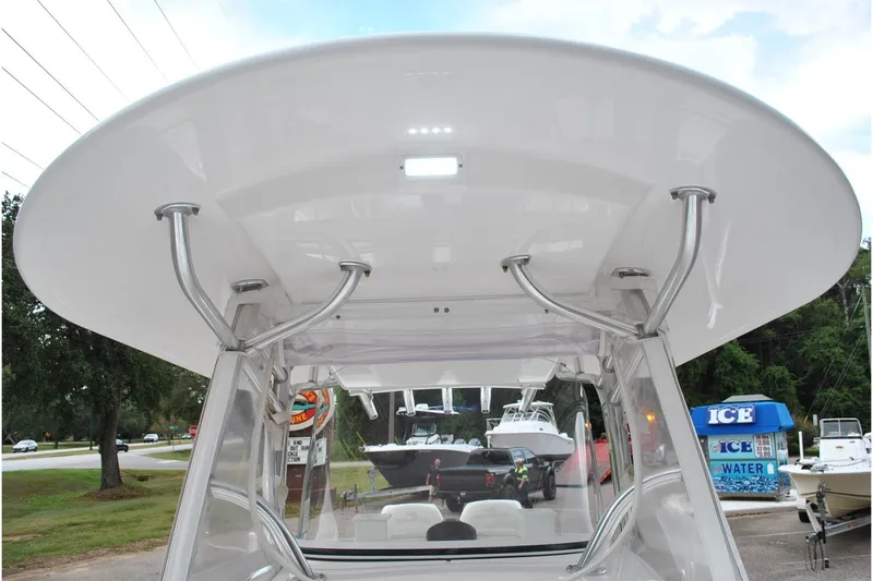 Slide: The Image of 2016 Regulator 28 Forward Seating boat with T-top and rod holders, docked near ice vendor. - 29