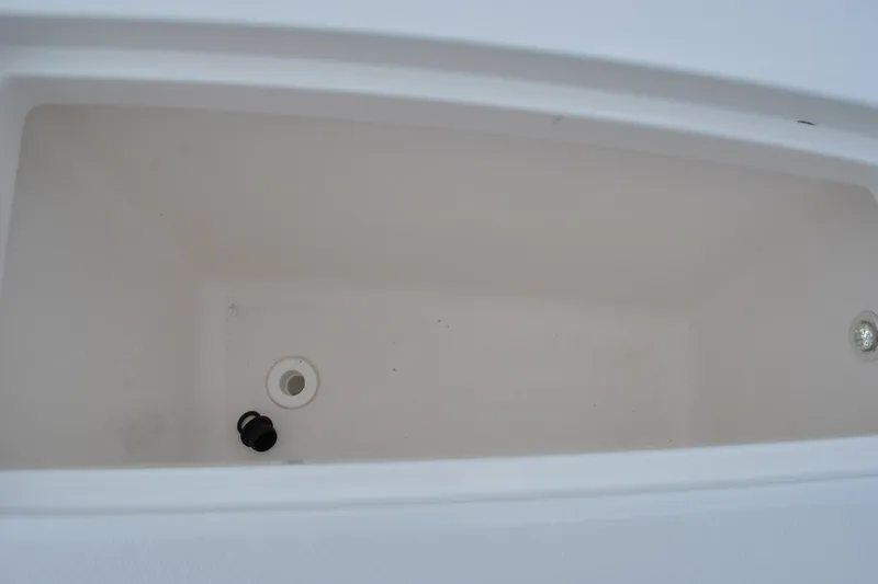 Slide: The Image of 2016 Regulator 28 Forward Seating storage compartment, white interior, drain plug visible. - 36