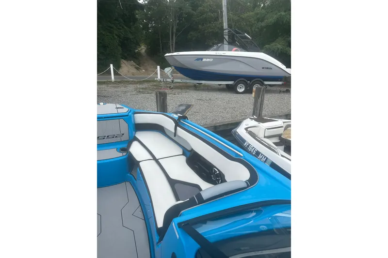 Slide: The Image of 2021 Yamaha Boats 255XE with sleek blue and white interior, docked near another boat. - 12